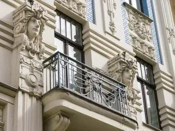 Ein Balkon an der Seite eines Gebäudes mit einer Frauenstatue darauf.