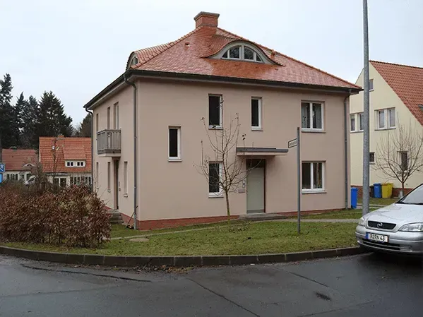 Ein weißes Auto steht vor einem großen Haus