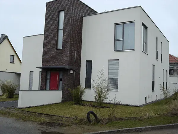 Ein weißes Haus mit einer roten Tür und vielen Fenstern