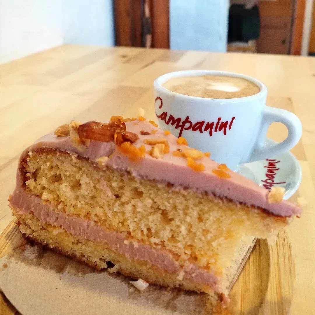 Pastel con glaseado rosa y nueces, y capuchino en taza