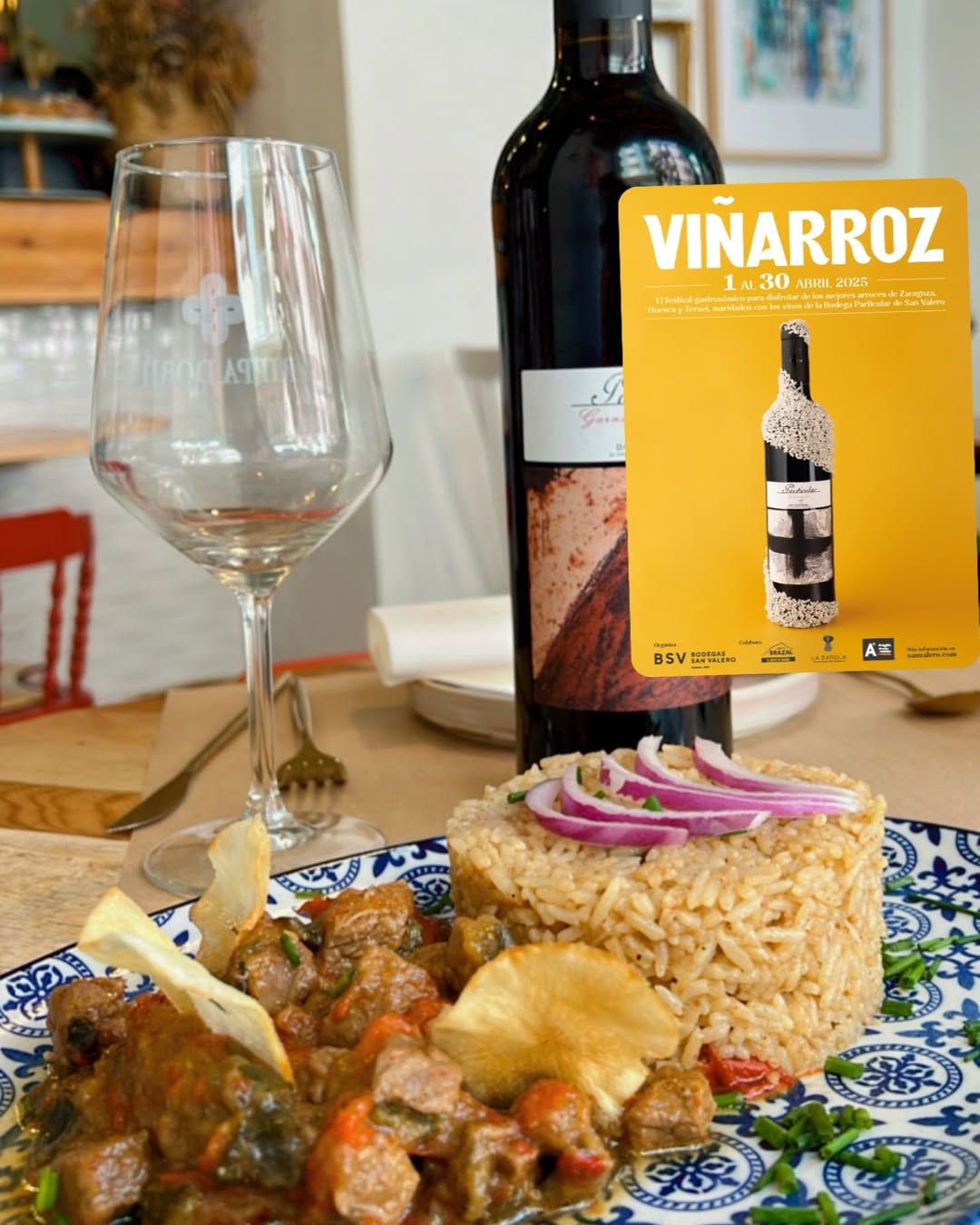Plato de comida con arroz, cebolla roja, botella de vino, copa y tarjeta con la inscripción