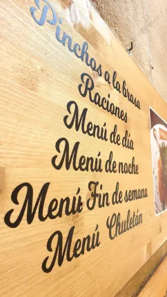 Letrero de madera con opciones de menú del restaurante, en español. 