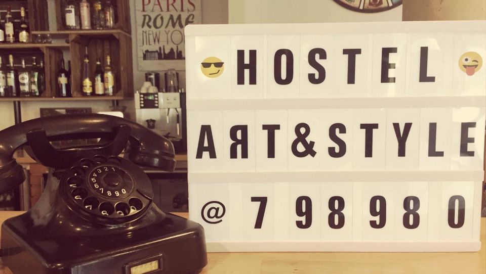 Ein Telefon liegt neben einem Schild mit der Aufschrift „Hostel Art & Style“