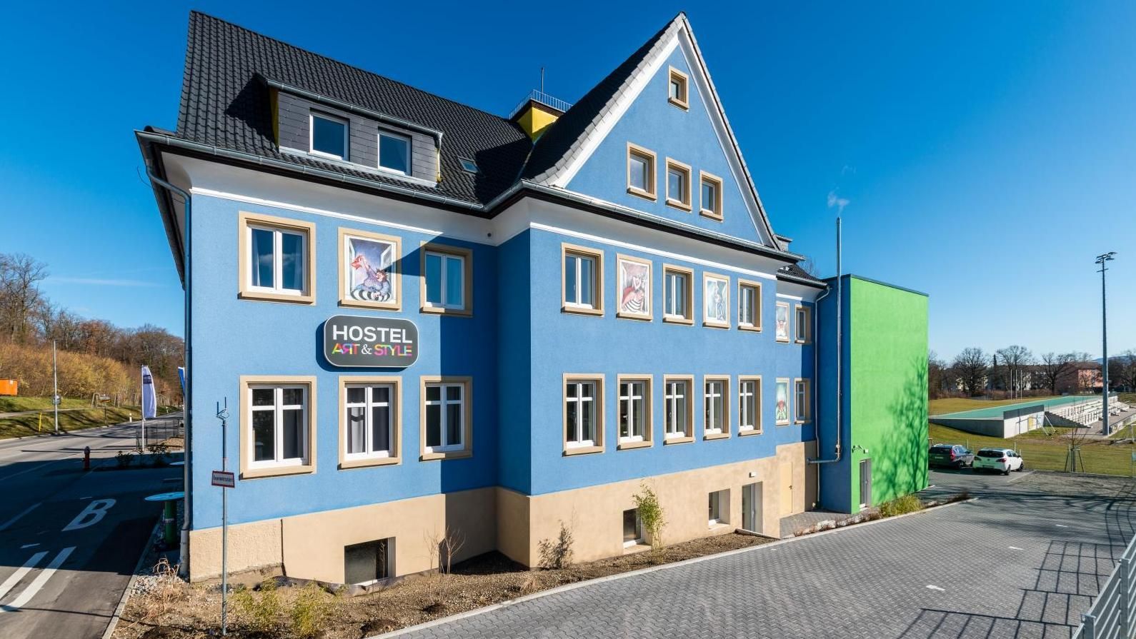 Un grand bâtiment bleu avec beaucoup de fenêtres se trouve au bord d'une route.