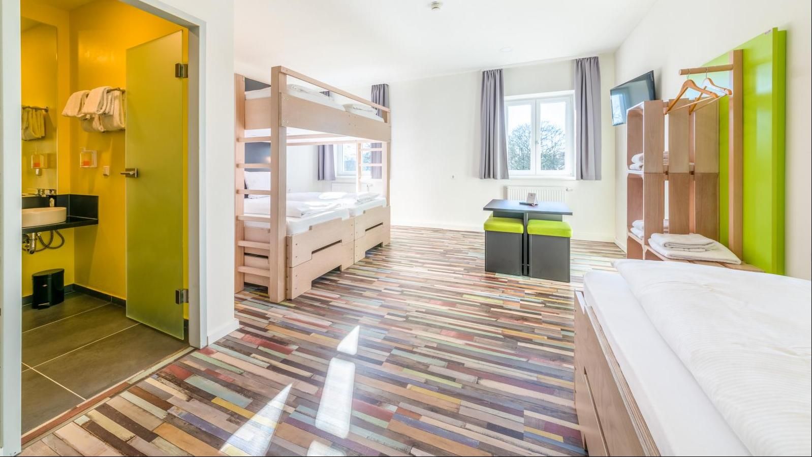 Chambre d'auberge avec lits superposés, un lit simple, une petite table et une salle de bains.