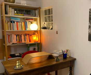 Un bureau à domicile confortable avec des étagères, une lampe à la lumière chaude et un bureau en bois avec des papiers et des stylos.