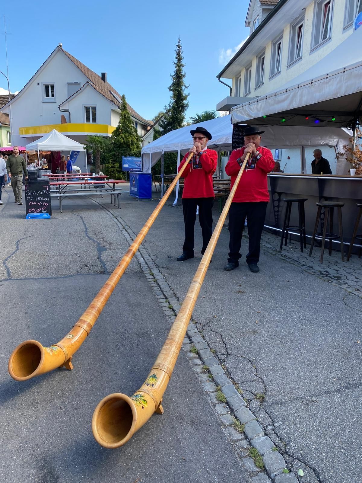 Zwei Frauen posieren an einer Bar, hinter ihnen stehen Gläser und Flaschen in Regalen.