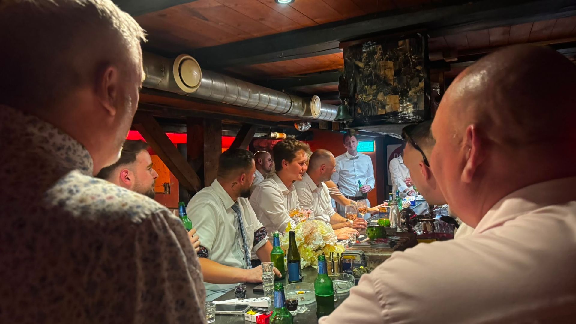 Das Interieur einer Retro-Bar ist schwach beleuchtet und mit roten Neonlichtern, Holztischen und einem Billardtisch auf der rechten Seite ausgestattet.