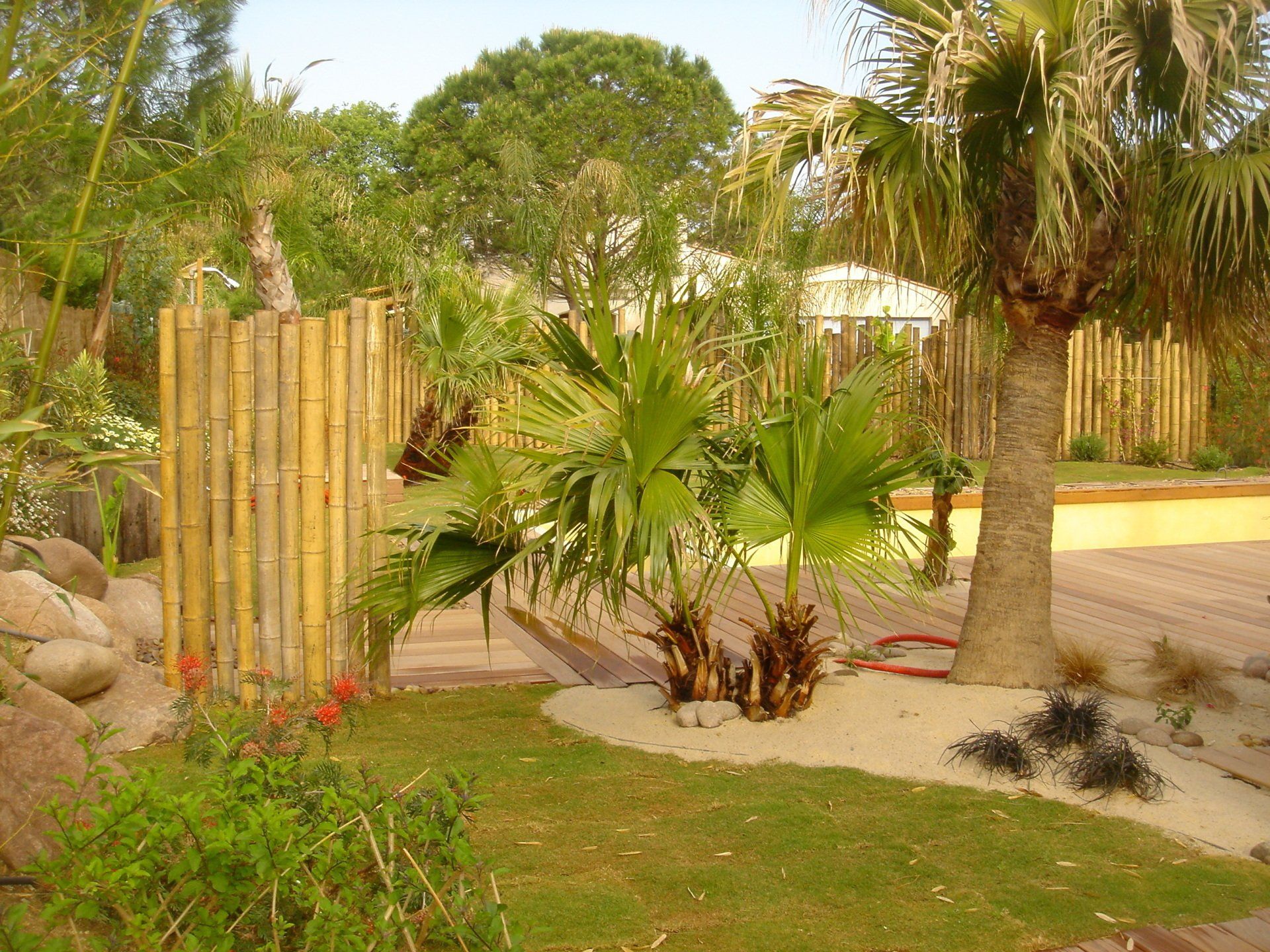 Jardin exotique avec plantations tropicales et palissade en bambou