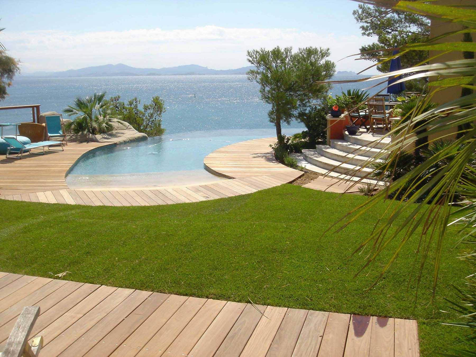 Piscine naturelle avec terrasse en bois et vue sur la mer