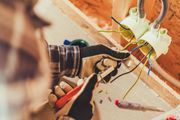 Un hombre está trabajando en una pared con un taladro y alicates.
