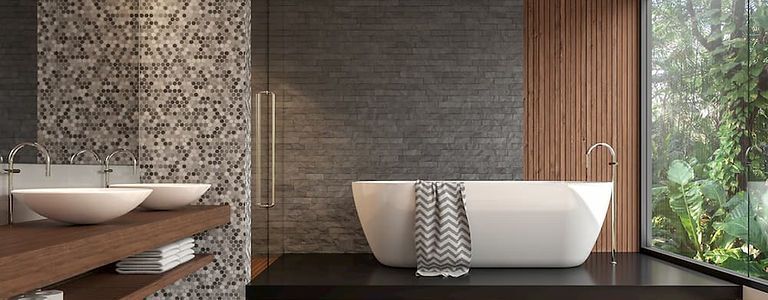Ein modernes Badezimmer mit freistehender weisser Badewanne, zwei Aufsatzwaschbecken auf einem Waschtisch aus Holz und einem großen Fenster mit Blick ins Grüne.