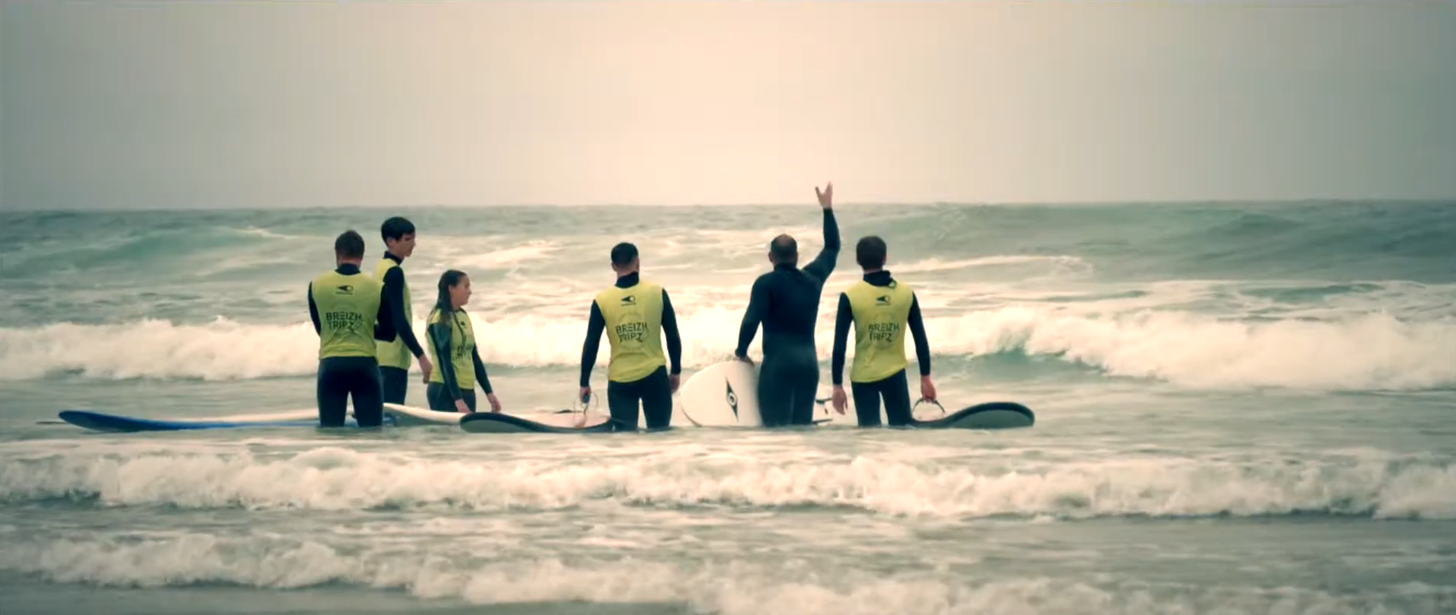 Quatre personnes vêtues de gilets de sauvetage jaunes se tiennent dans les vagues.