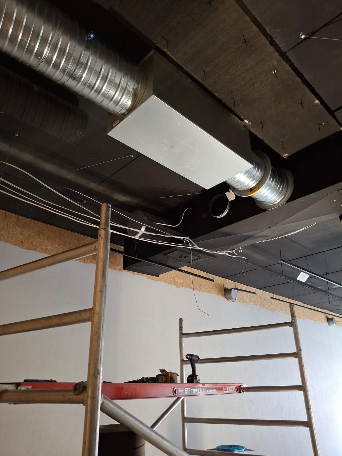 Kaksi pystysuoraa ruostumattomasta teräksestä valmistettua pakoputkea asennettuna harmaalle, uurteiselle metalliseinälle.