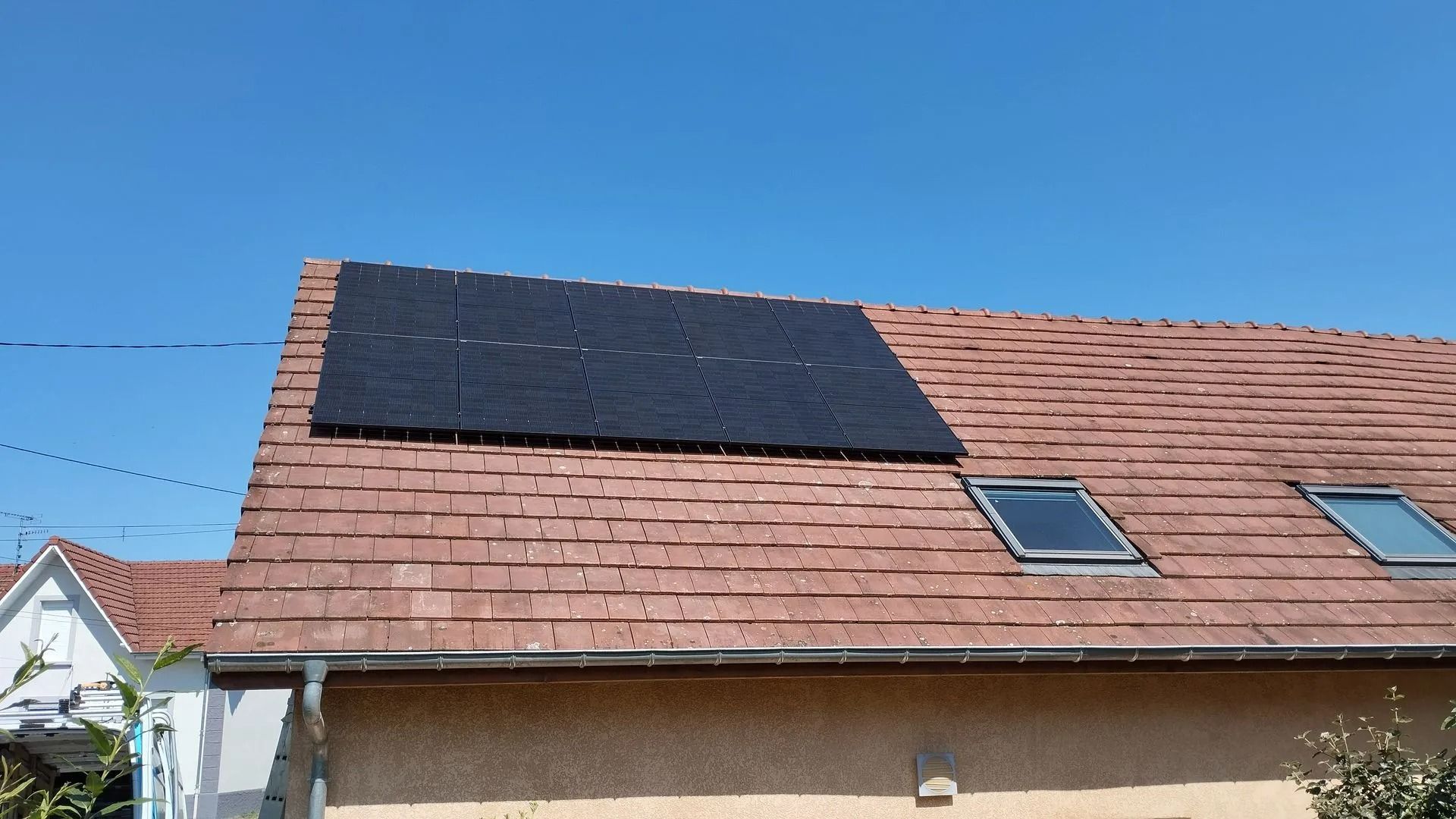 Panneaux photovoltaïques sur un toit de tuiles rouges.