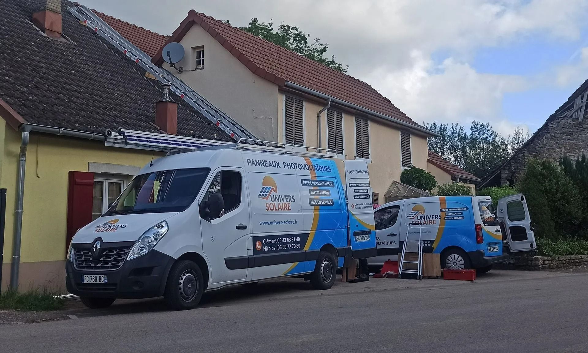 Trois fourgonnettes blanches de l'entreprise sont garées devant une maison ; des échelles sont posées sur l'une d'elles.
