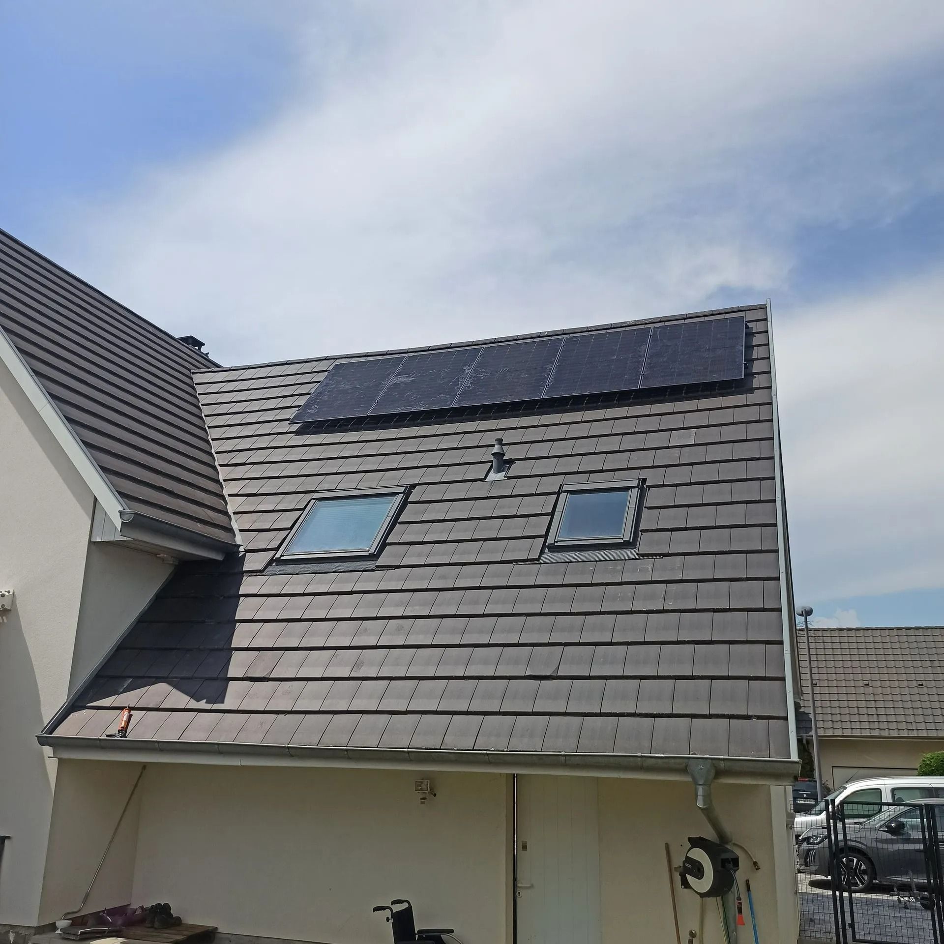 Panneaux photovoltaïques sur un toit de tuiles avec puits de lumière.