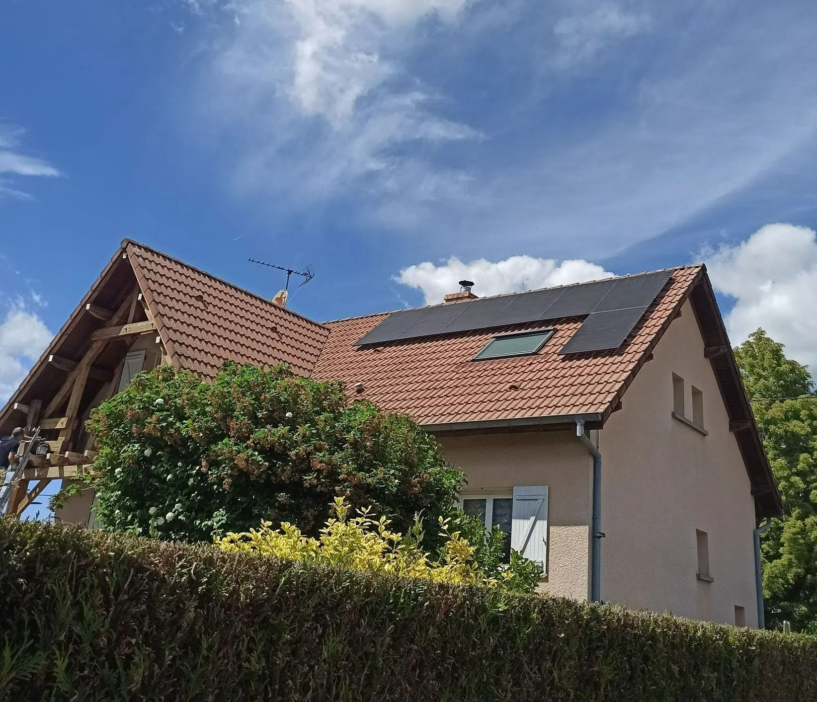 Maison au toit de tuiles rouges et panneaux photovoltaïques.