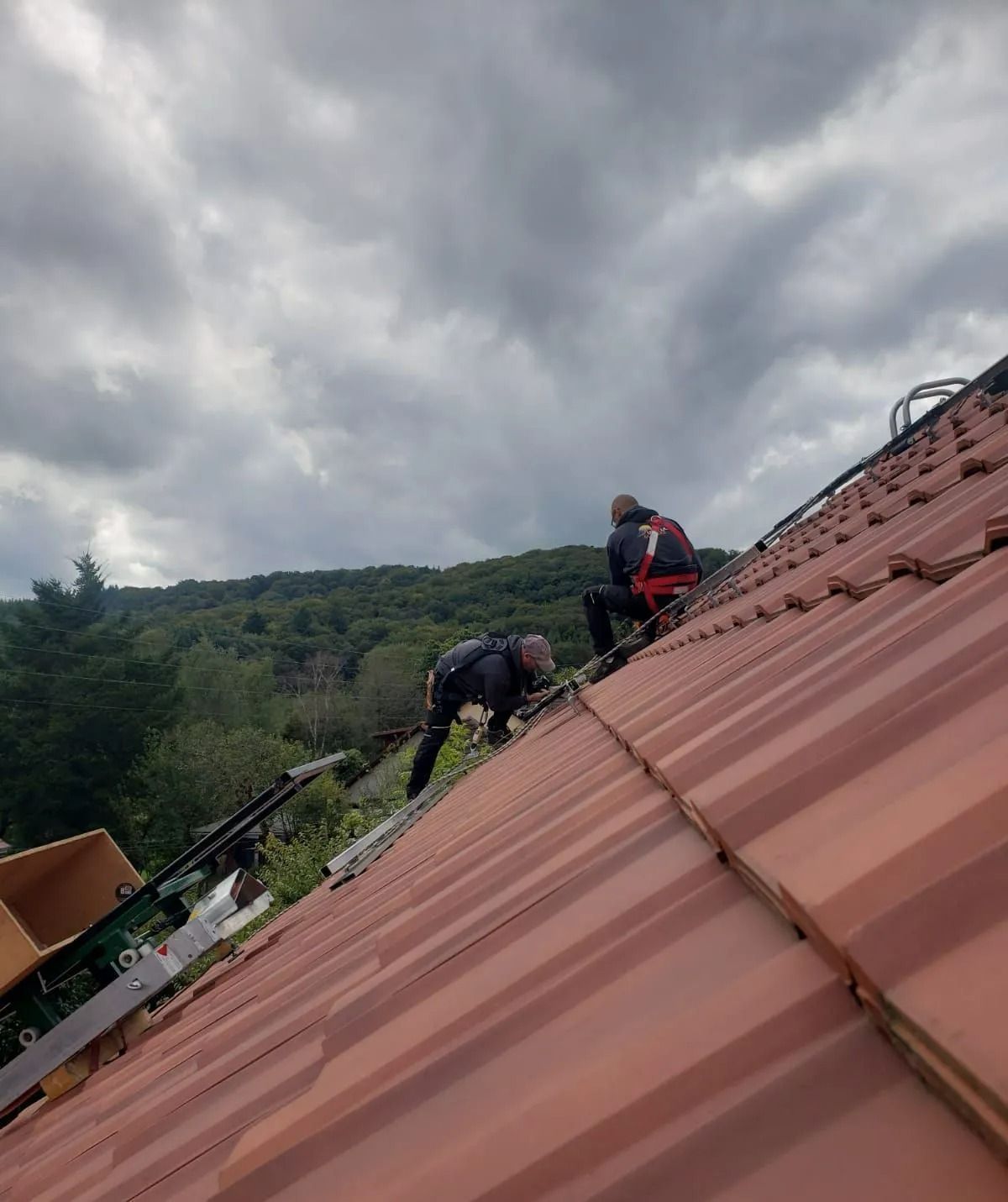 Deux ouvriers installent des panneaux photovoltaïques sur un toit de tuiles.