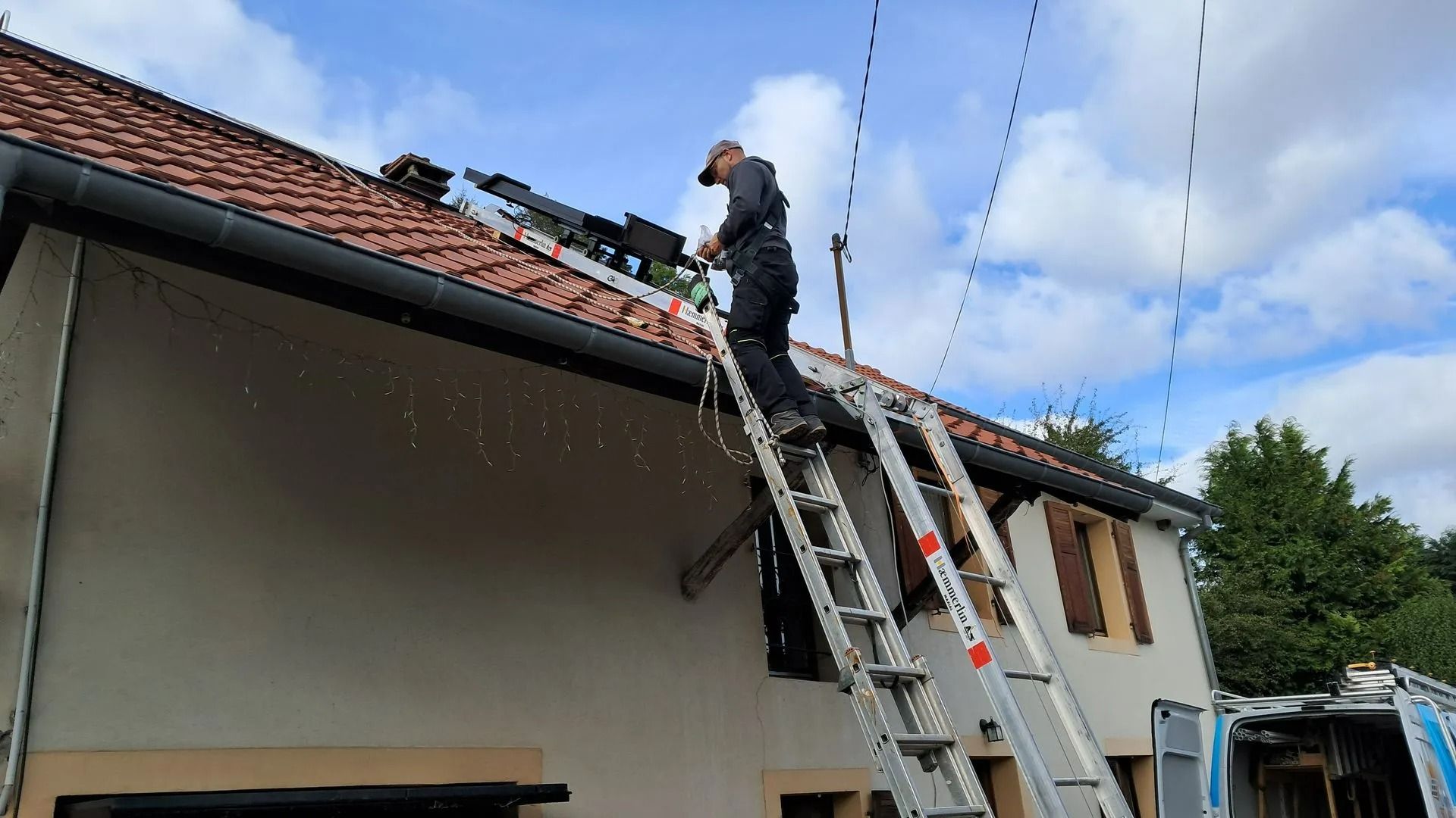 Une personne sur une échelle installe des panneaux photovoltaïques.