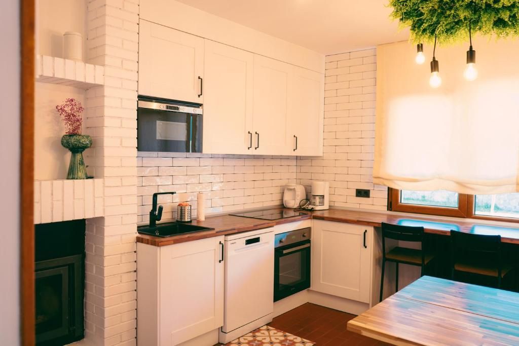 Una cocina con gabinetes blancos, un fregadero, un microondas y una mesa.