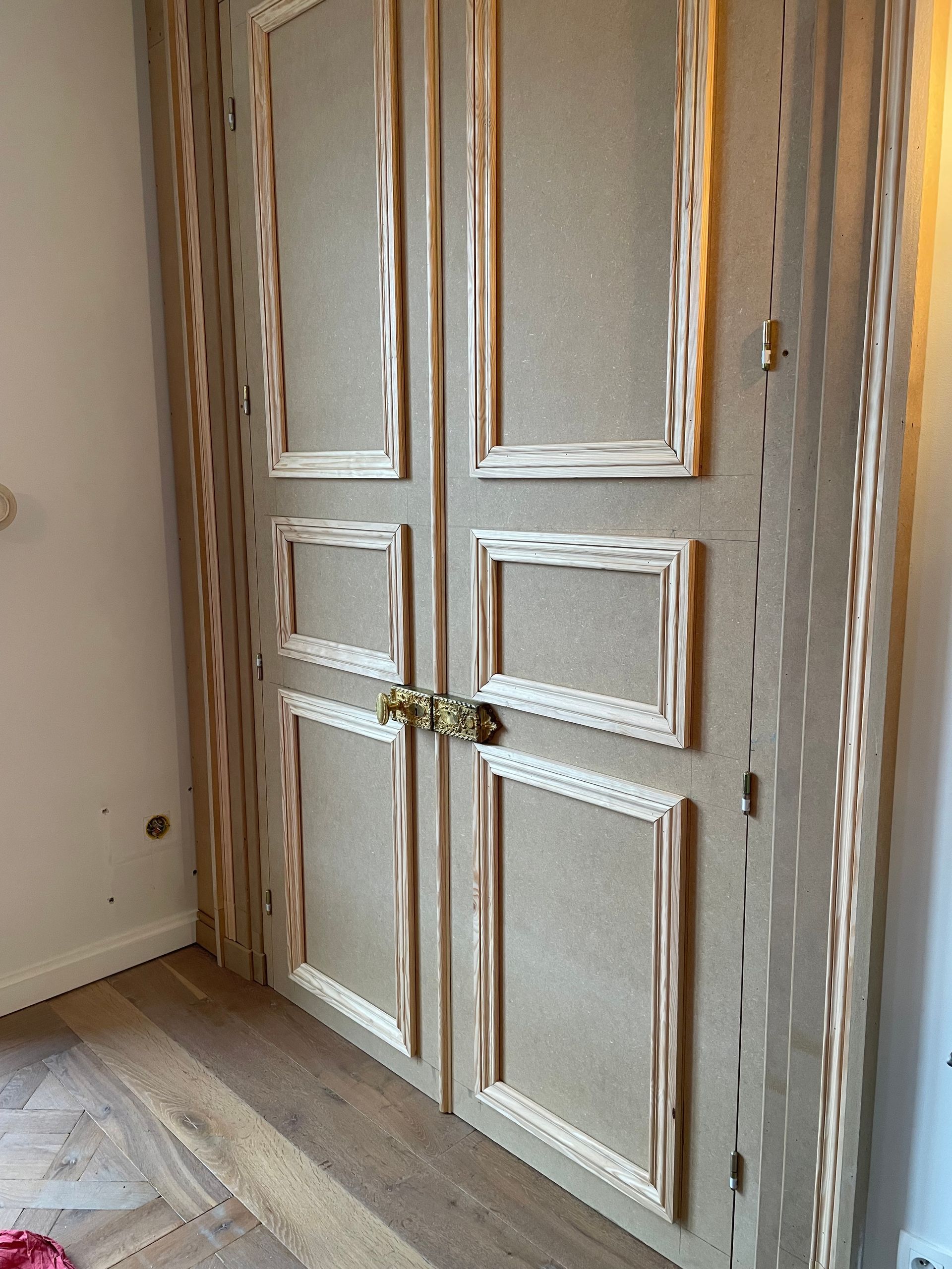 Placard à deux portes avec encadrement clair et poignée en laiton.