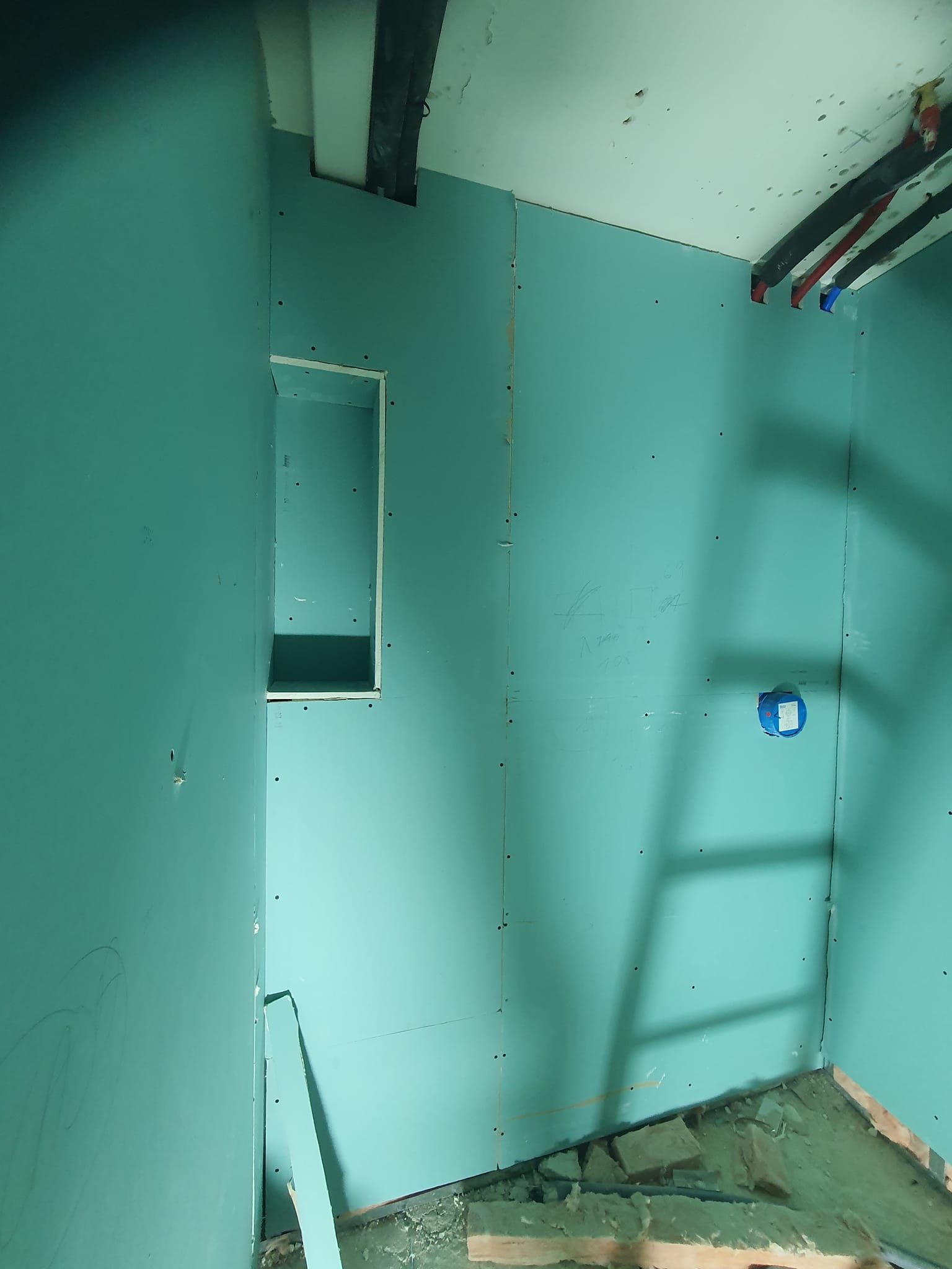 Panel de yeso verde instalado en un baño con nicho, construcción parcialmente terminada.