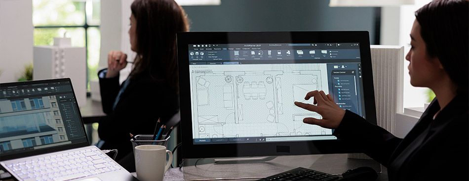 Femme pointant un écran d'ordinateur sur lequel se trouve un plan 2D