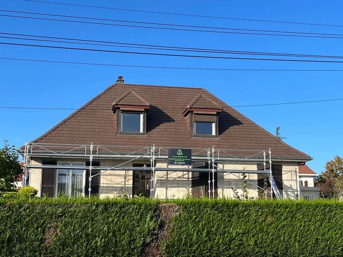 Maison avec un toit brun et un échafaudage.