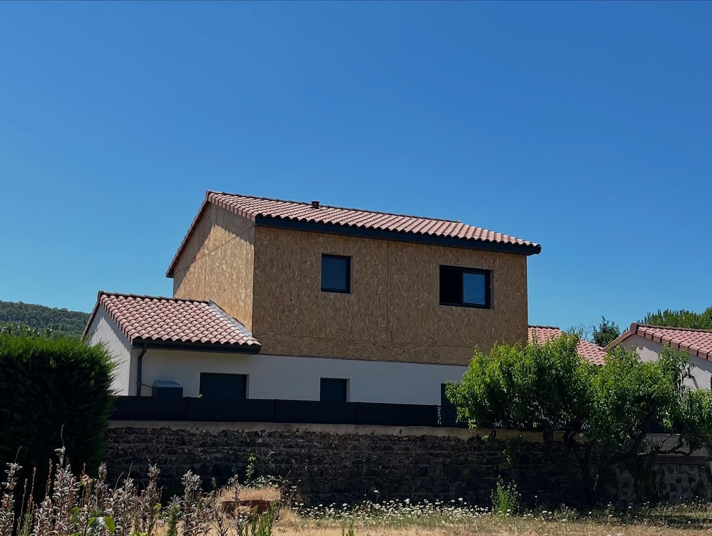 Extension d'une maison avec une ossature en bois et un toit en tuiles rouges.