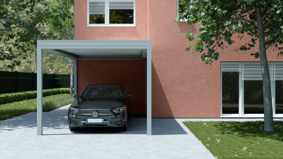 Voiture noire garée sous l'abri d'une maison moderne, à côté d'un mur extérieur rose et d'une pelouse.