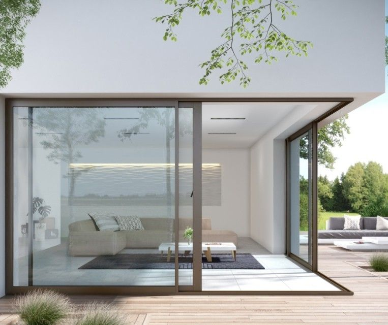 Salon moderne aux parois de verre s'ouvrant sur une terrasse en bois et un jardin sous un auvent blanc.