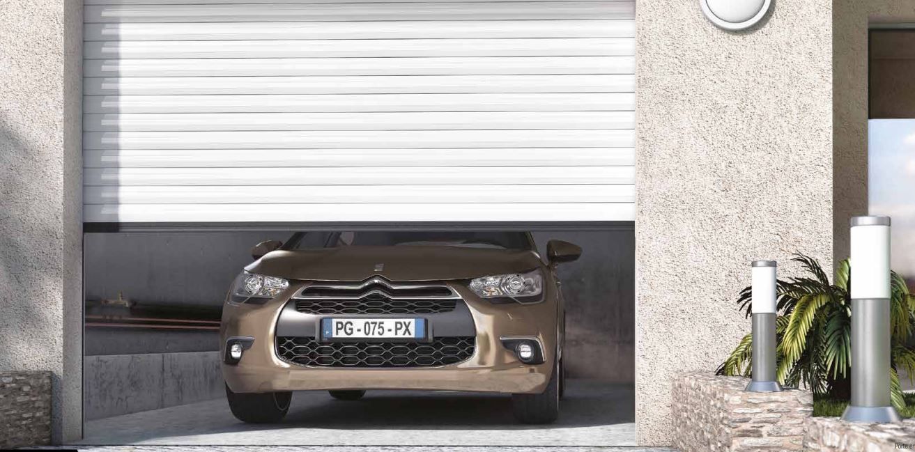 Voiture de sport marron garée dans un garage étroit sous une porte blanche fermée