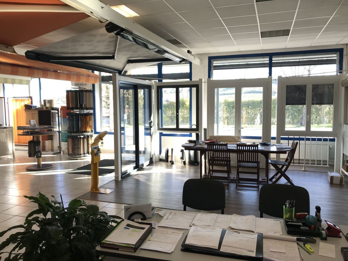 Espace de détente ouvert avec tables, chaises, plantes et grandes fenêtres donnant sur les arbres