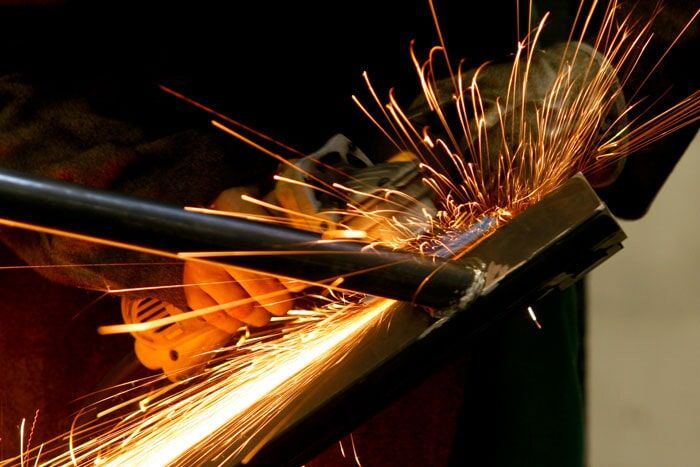 Uma pessoa está triturando um pedaço de metal com faíscas saindo dele