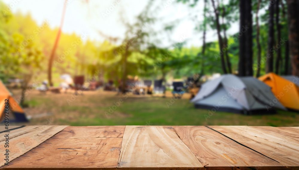 Tavolo di legno davanti a un campeggio soleggiato con tende e alberi sullo sfondo.