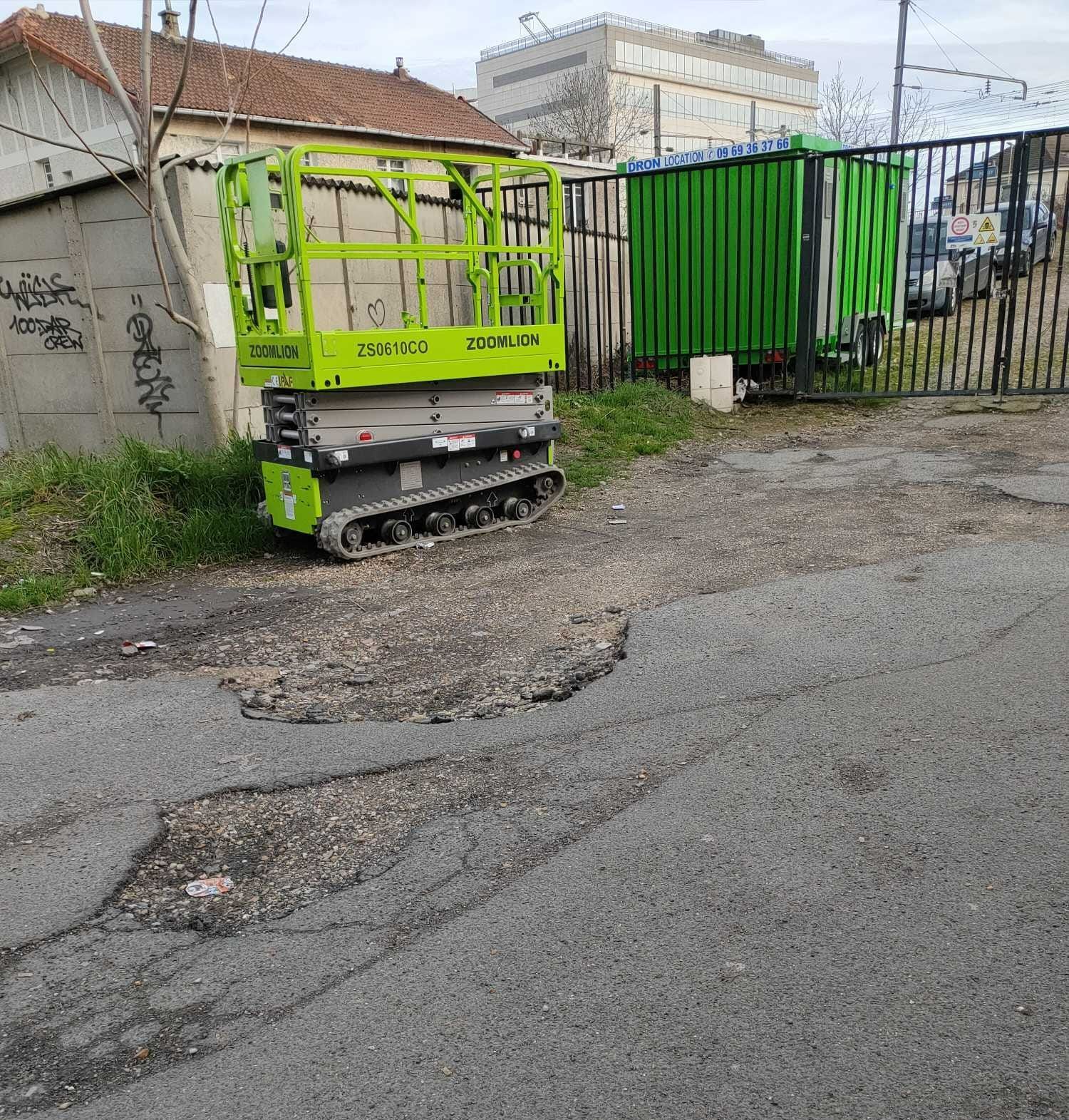 Nacelle ciseau devant une grille