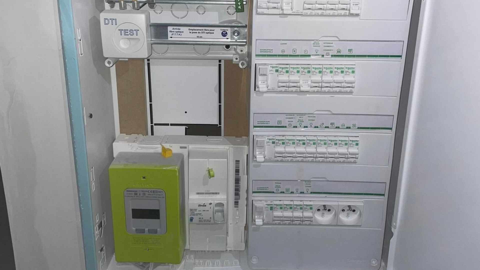 Tableau électrique avec compteurs et disjoncteurs dans un boîtier mural.