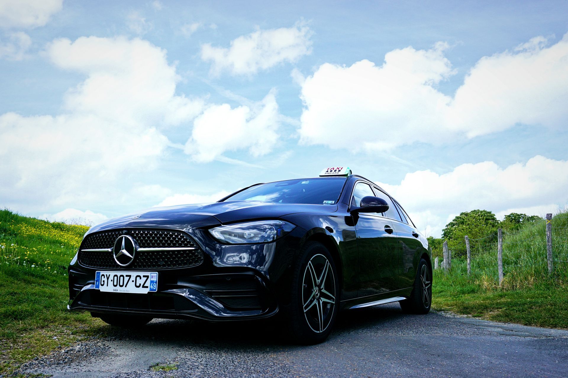 Un SUV Mercedes noir garé sur une route de campagne sous un ciel nuageux et lumineux