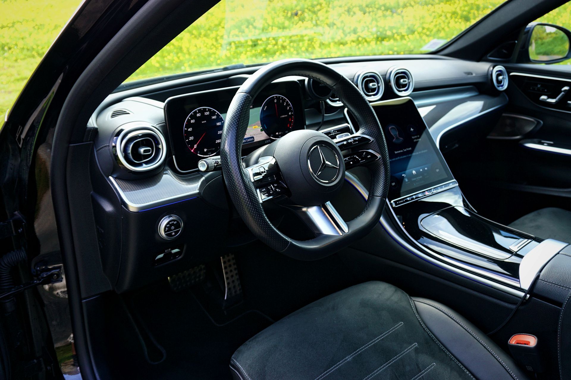 Intérieur d'une Mercedes noire avec tableau de bord, volant et console centrale visibles.