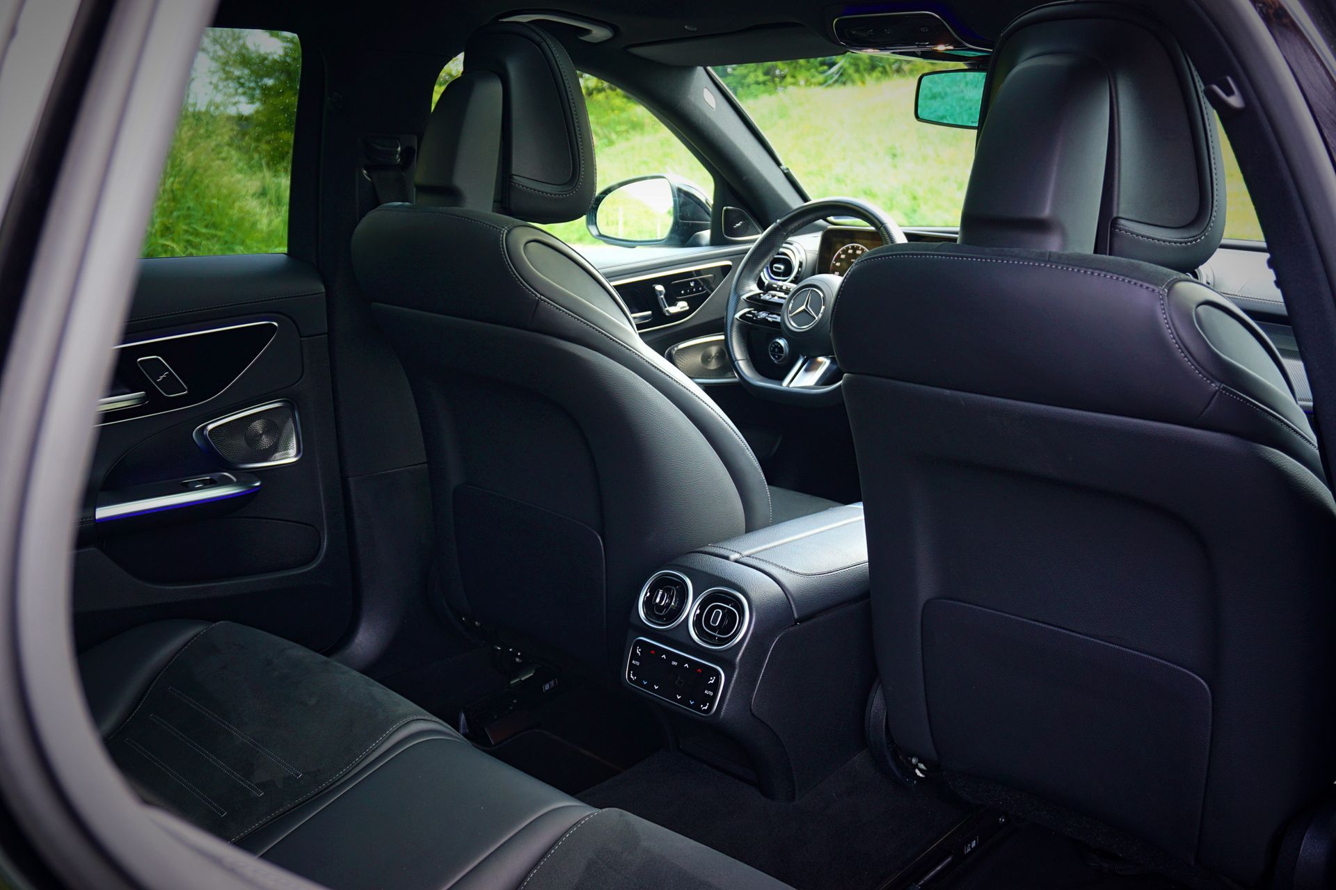 Intérieur de la voiture vu depuis la banquette arrière, montrant les sièges en cuir noir et le tableau de bord avant