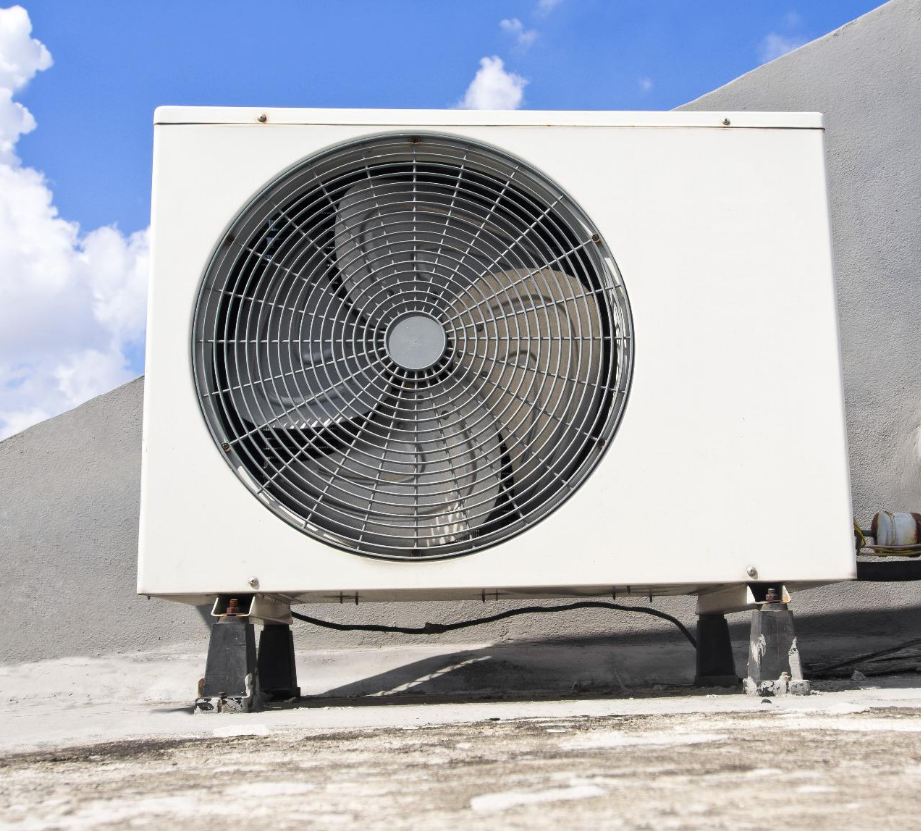 Un technicien en uniforme et casquette bleus effectue l'entretien d'un climatiseur mural.