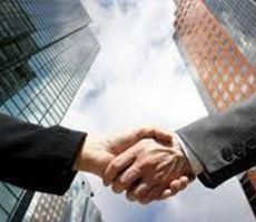 Dos personas se dan la mano frente a altos edificios de oficinas.