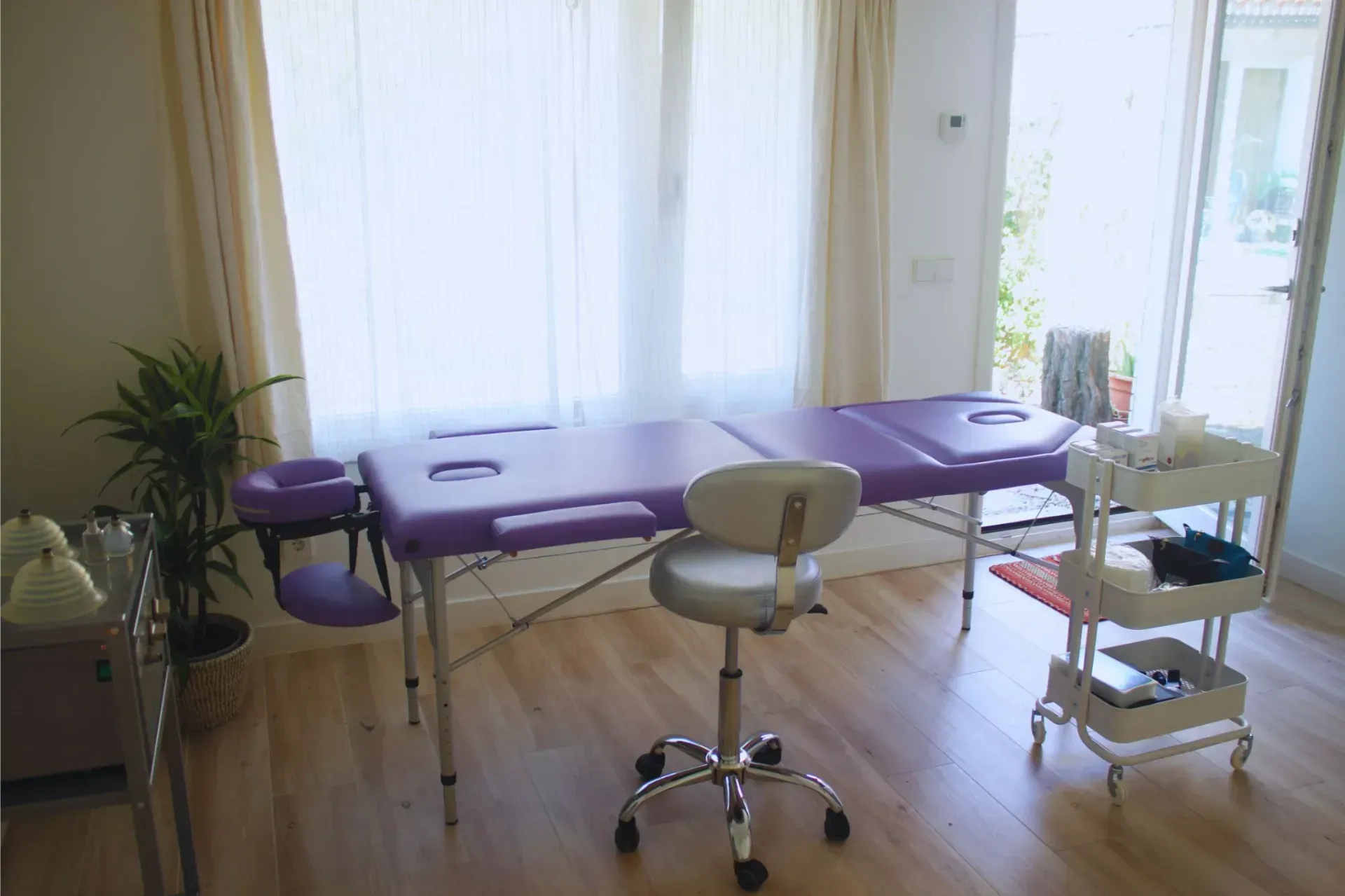 Una habitación con una mesa de masaje morada y una silla blanca.