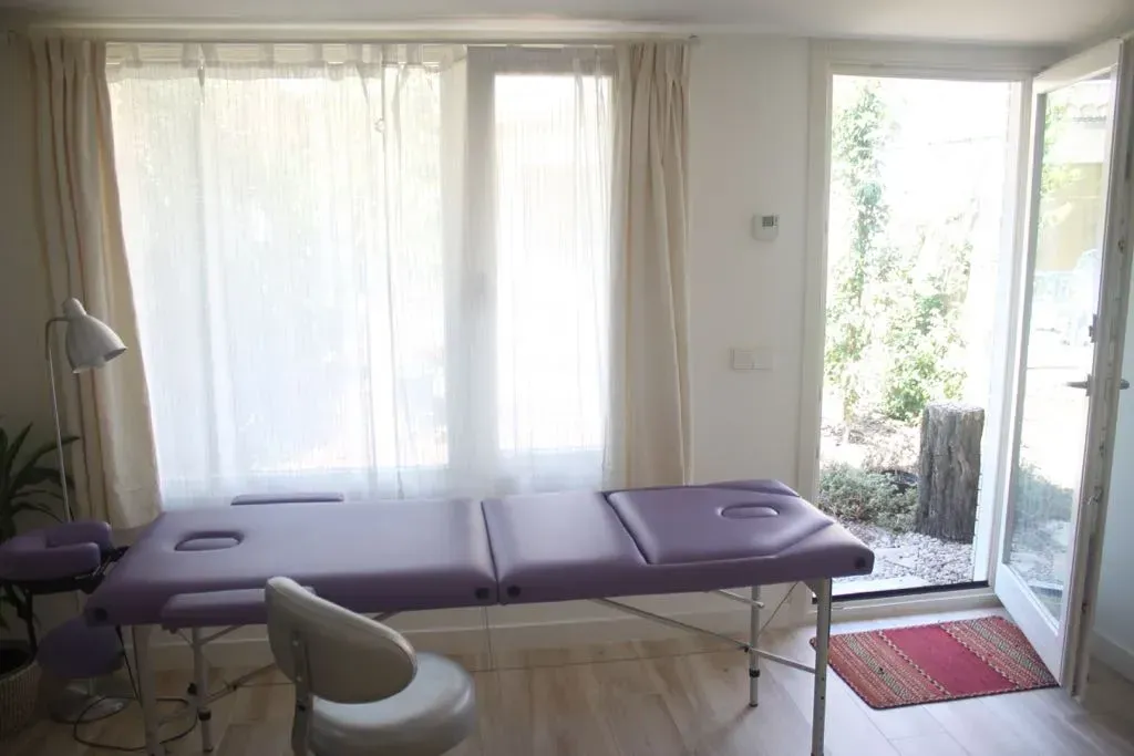 Una mesa de masaje morada en una habitación con una silla.