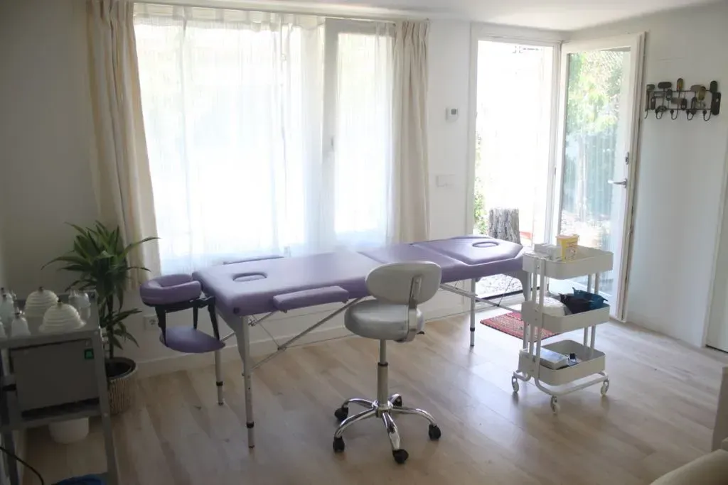 Una habitación con dos mesas de masaje y una silla.