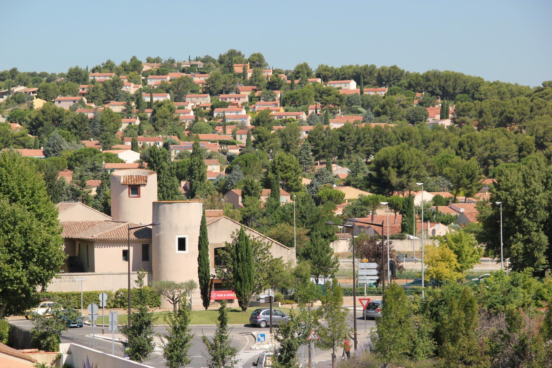Quartier à flanc de colline avec des maisons aux toits de tuiles et des arbres verdoyants luxuriants par une journée ensoleillée