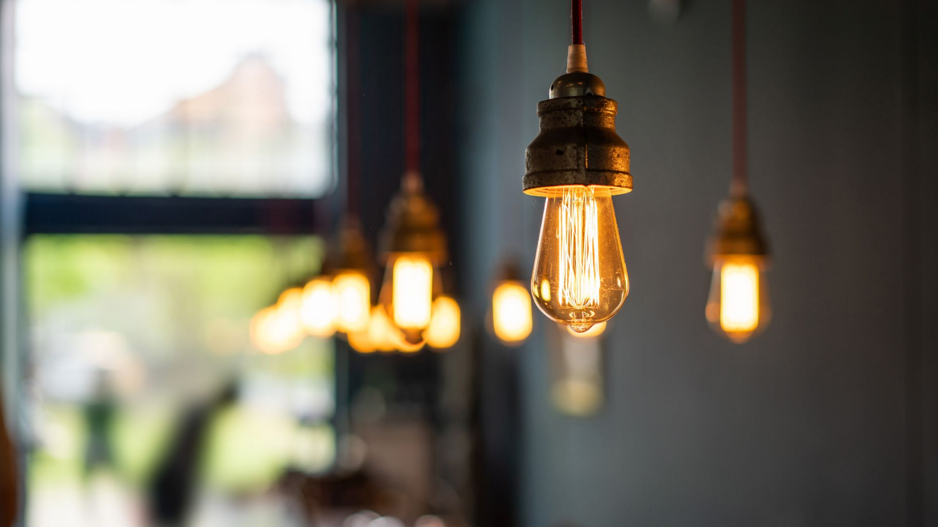 Des ampoules Edison à la lumière chaude sont suspendues à l'intérieur, l'une d'elles brillant de façon prédominante au premier plan.