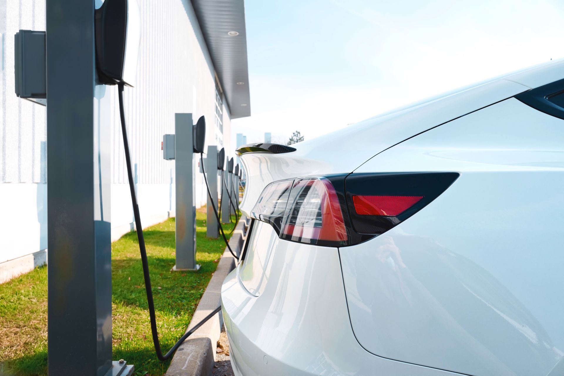 Voiture électrique blanche en charge à une borne située à côté d'un bâtiment extérieur