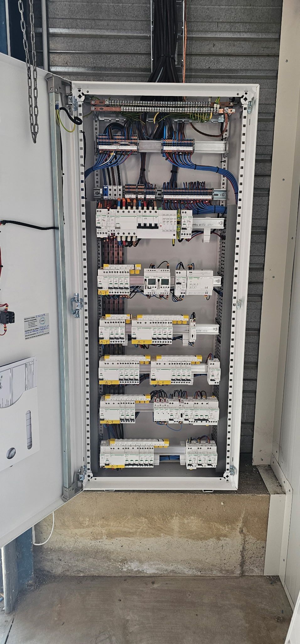 Tableau électrique ouvert avec disjoncteurs et câblage dans un placard technique